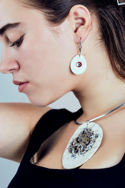 Orecchini in ceramica Raku con pendente bianco ovale in cui è incastonata una piccola murrina blu e rossa