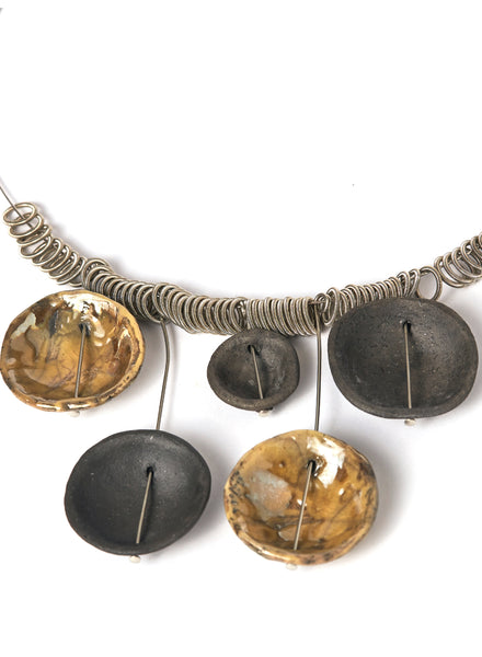 Collana realizzata a mano con cinque ciondoli in ceramica Raku, ciascuno unico nelle sfumature e nelle imperfezioni, sospesi su un elegante girocollo in acciaio.