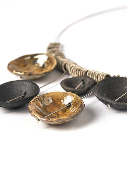 Collana realizzata a mano con cinque ciondoli in ceramica Raku, ciascuno unico nelle sfumature e nelle imperfezioni, sospesi su un elegante girocollo in acciaio.