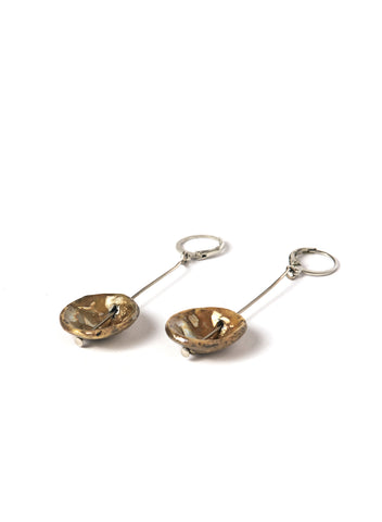 Orecchini realizzati a mano con elementi pendenti con calde sfumature color oro in ceramica Raku montati su un gancio rotondo.
