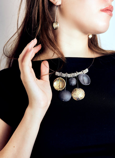 Collana realizzata a mano con cinque ciondoli in ceramica Raku, ciascuno unico nelle sfumature e nelle imperfezioni, sospesi su un elegante girocollo in acciaio.