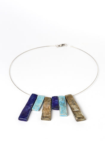 Collana in ceramica Raku con strisce verticali nei toni dell’oro, dell’azzurro e del blu profondo. 