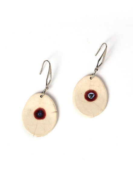 Orecchini in ceramica Raku con pendente bianco ovale in cui è incastonata una piccola murrina blu e rossa