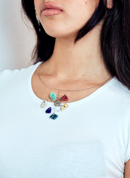 Collana leggera e contemporanea con filo d'acciaio armonico che lega un insieme vivace di piccoli elementi in ceramica Raku smaltata. 