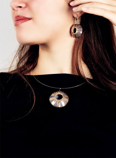 Collana realizzata a mano, con pendente in ceramica Raku di forma circolare oro e nero fumo.