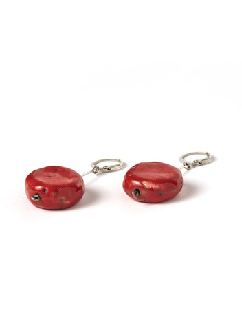 Orecchini artigianali con pendente lungo in acciaio e disco rosso in ceramica Raku, montati su un gancio rotondo.