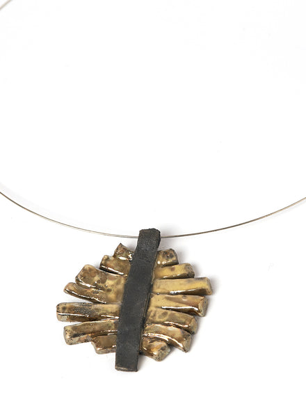 Collana con pendente in ceramica Raku con strisce oro cangiante che si appoggiano su una base nero fumo. 