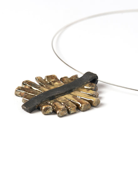Collana con pendente in ceramica Raku con strisce oro cangiante che si appoggiano su una base nero fumo. 