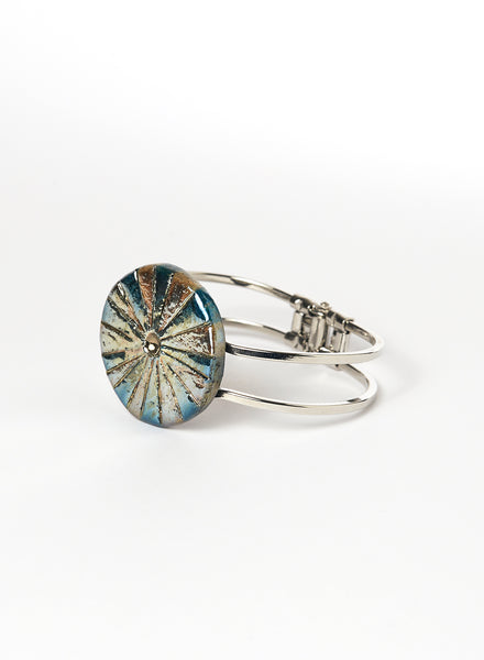 Bracciale rigido in lega con elemento in ceramica Raku, caratterizzato da un disco con luminose striature dorate.