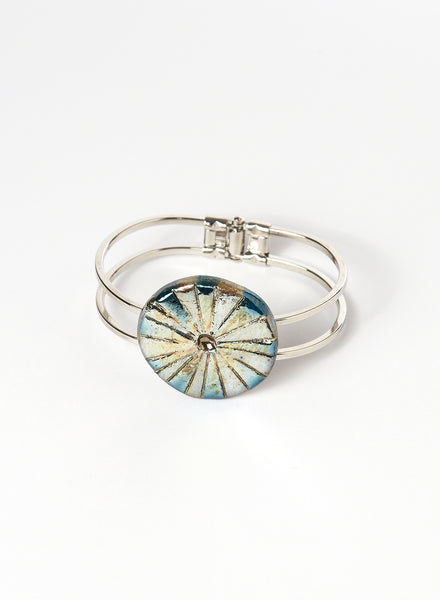 Bracciale rigido in lega con elemento in ceramica Raku, caratterizzato da un disco con luminose striature dorate.