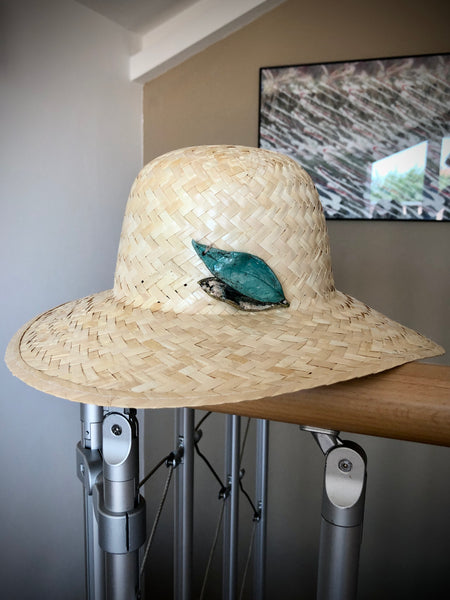 cappello in paglia naturale con accessorio-gioiello fatto a mano in ceramica Raku. foglie azzurro e oro