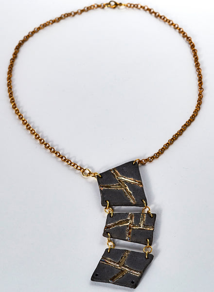 collana di forme geometriche fatta a mano in ceramica raku. nero e oro