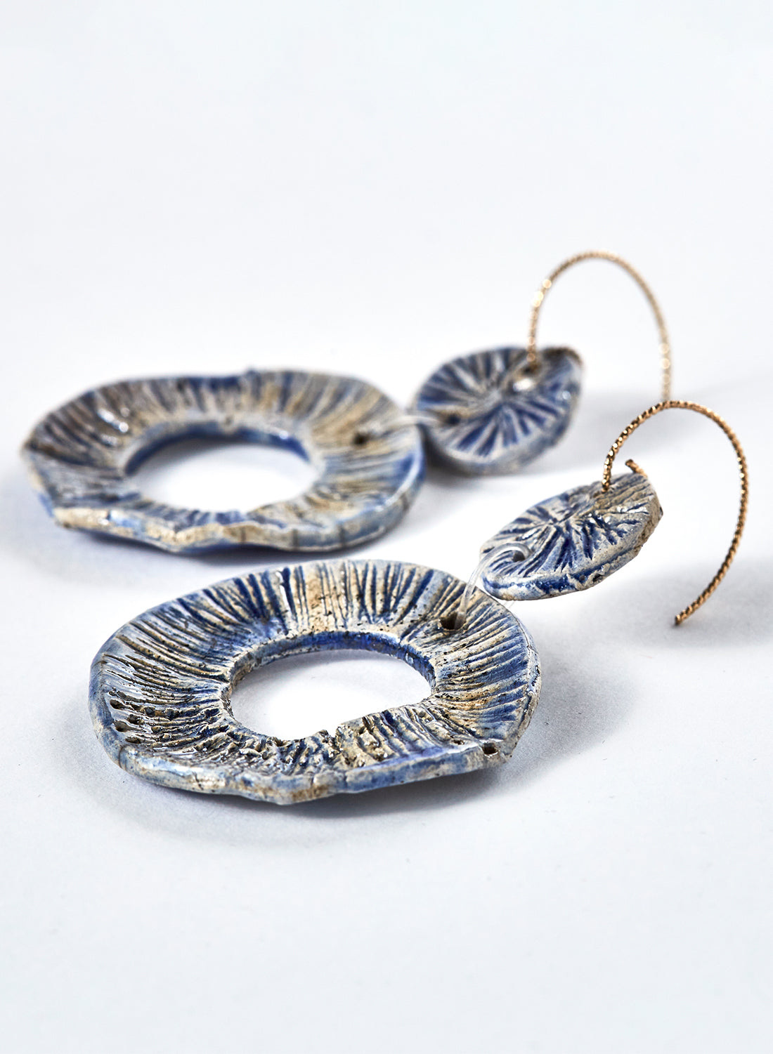 Orecchini a forma di ruota fatti a mano in ceramica raku azzurri con monachella in ottone.